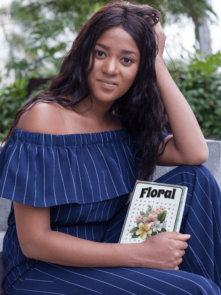 a young woman is smiling to the camera and holding a Floral Word Search Book.